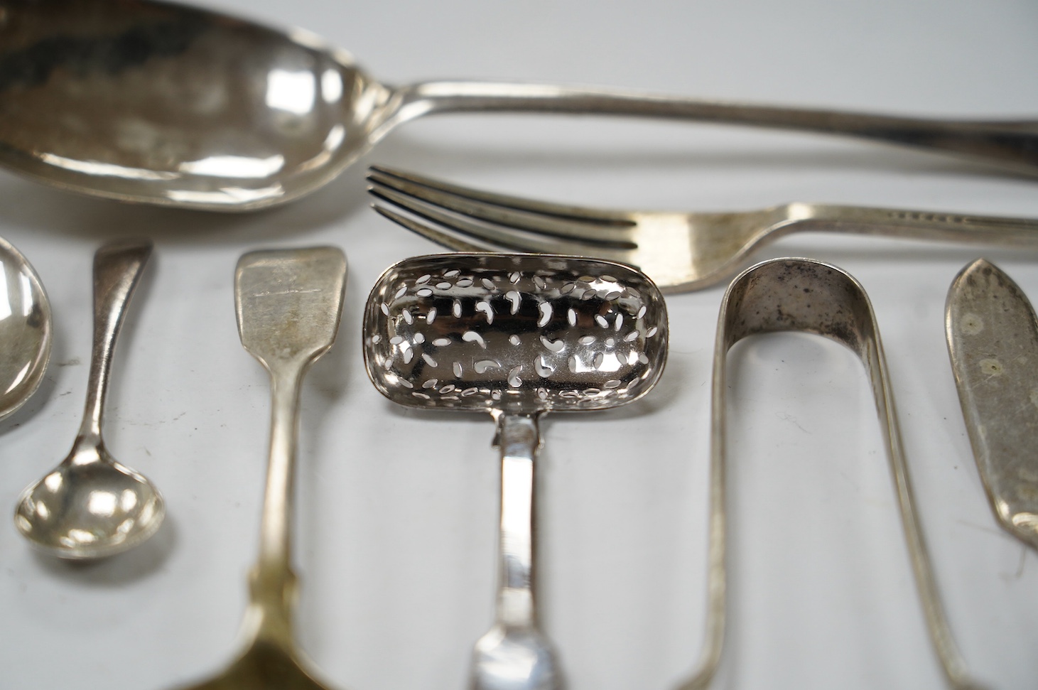 An early 18th century Hanovarian rat-tail pattern table spoon, indistinct marks, 19.6cm and a small quantity of later assorted silver flatware, 21.7oz. Condition - poor to fair